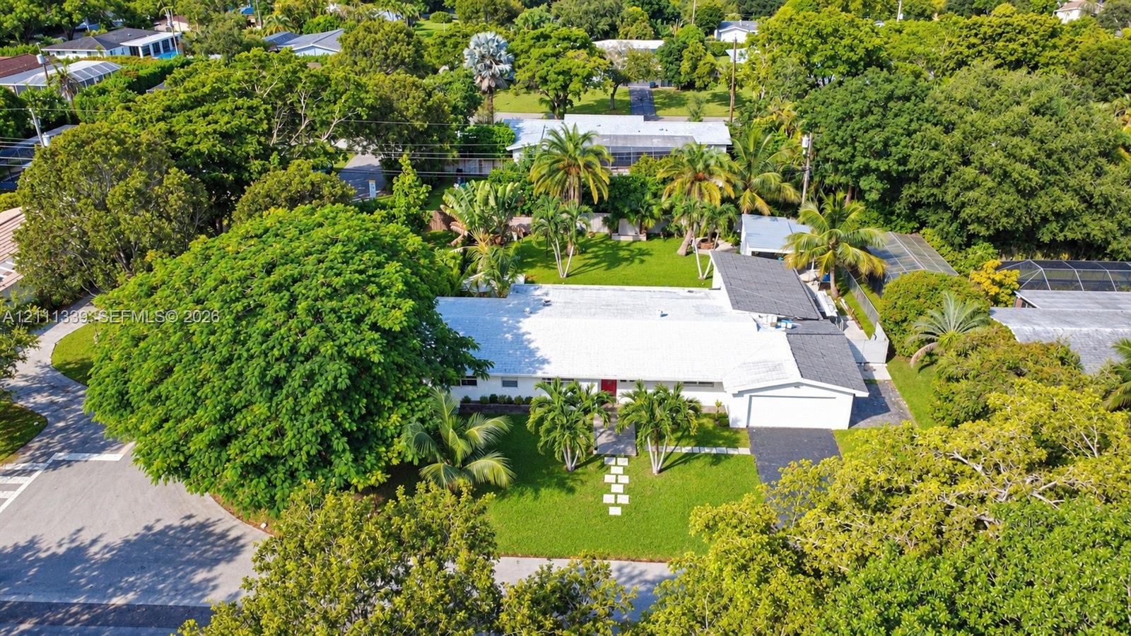 Expansive lot featuring mature landscaping, sprawling lawn, attached garage, and paved driveway