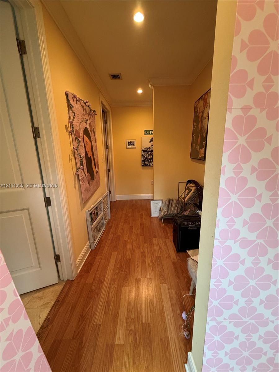 Hallway featuring wood-finish flooring, recessed ceiling lighting, and crown molding