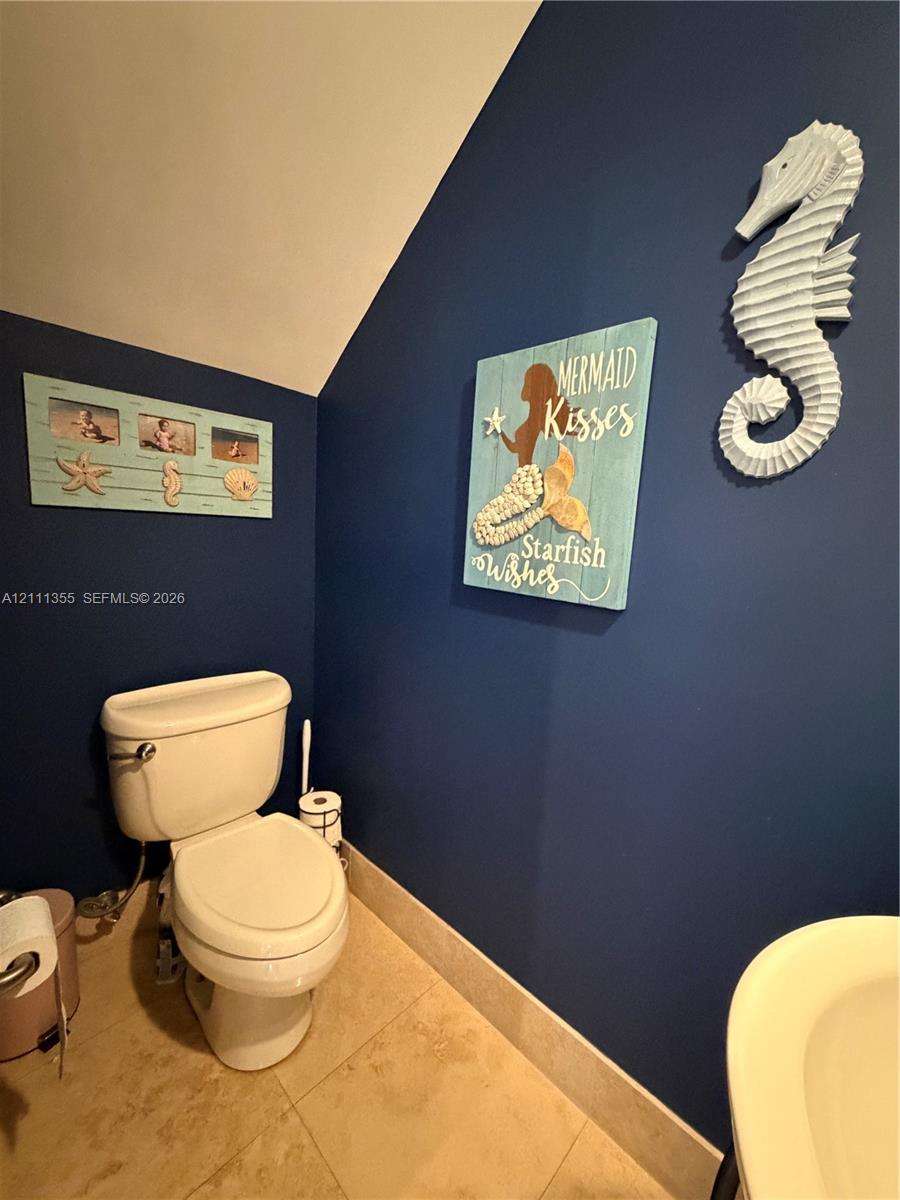 Restroom featuring bold navy blue wall paint and neutral stone-finish floor tiling