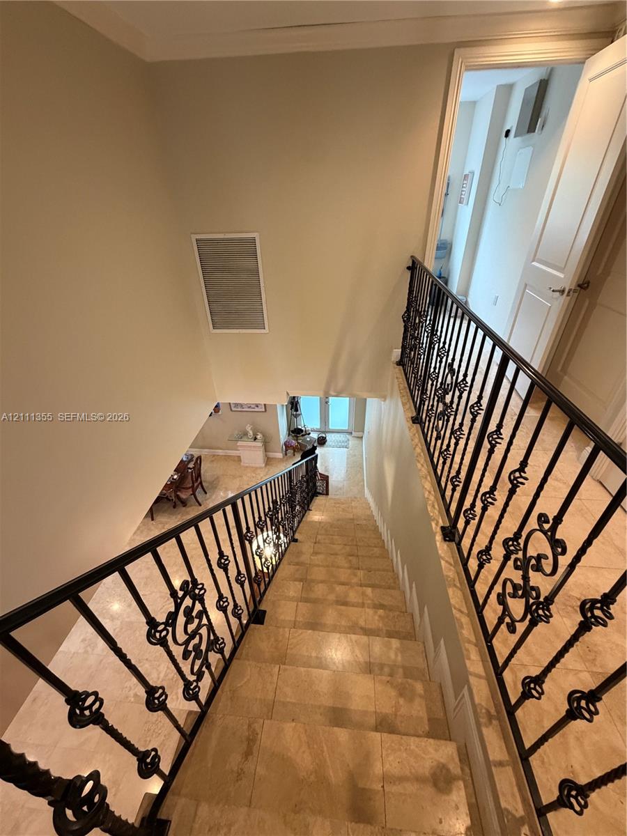 Staircase featuring stone-finish treads and ornate black metal balusters