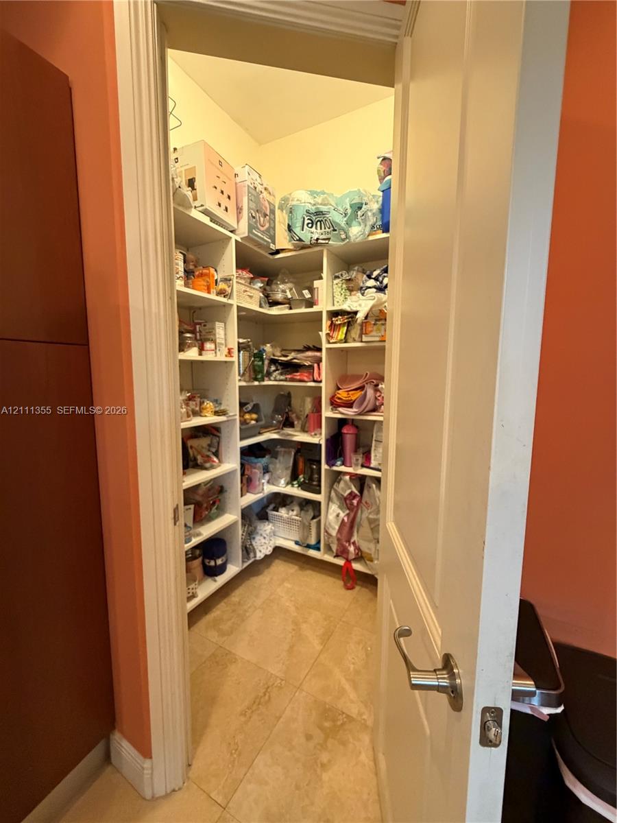 Walk-in pantry featuring built-in shelving and tile flooring