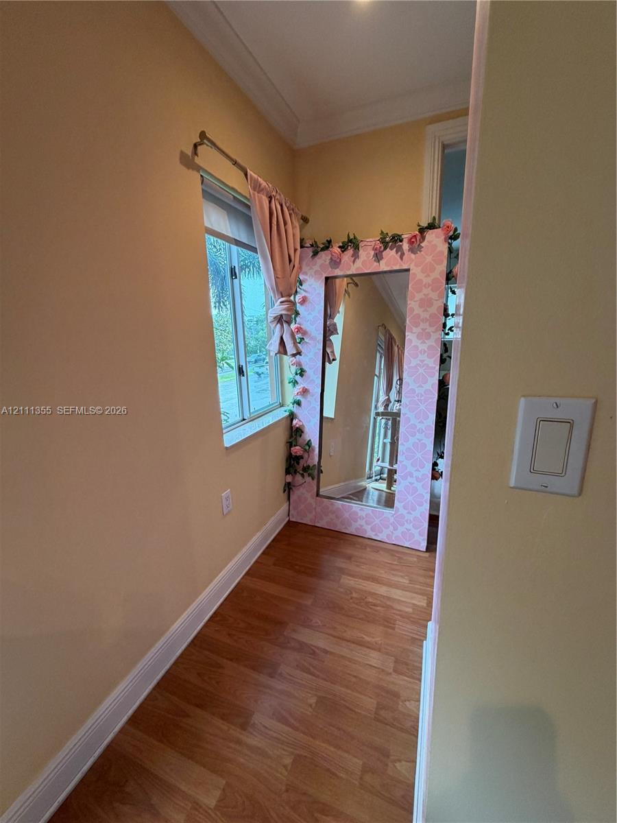 Wood-finish flooring, crown molding, and a single-pane window