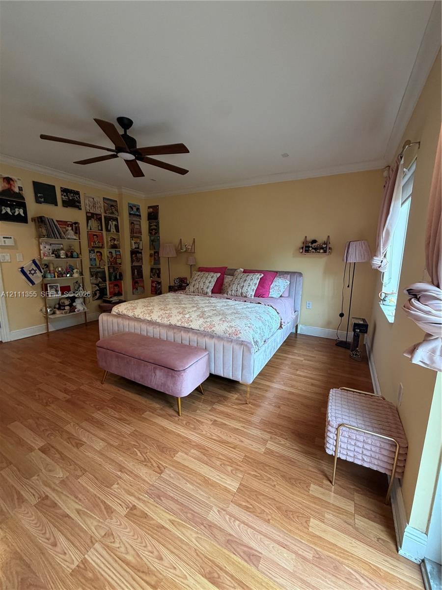 Wood-finish flooring, matte black ceiling fan, and crown molding