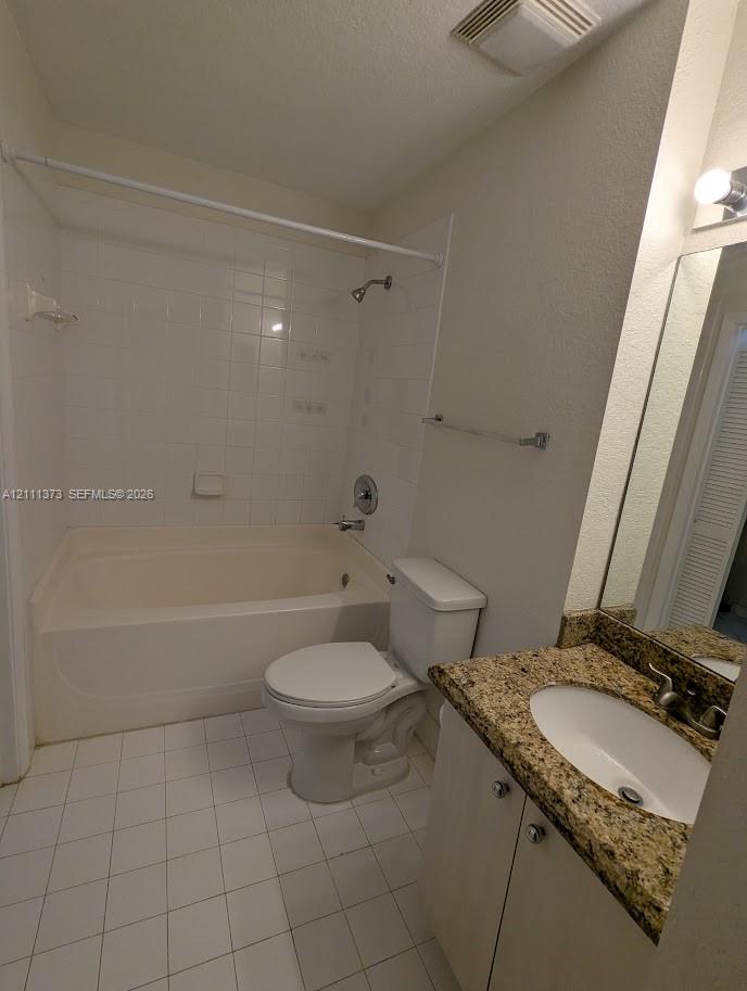 Bathroom featuring a stone-look countertop vanity, an integrated oval sink, a shower-tub combination with white tile surround, and neutral floor tile