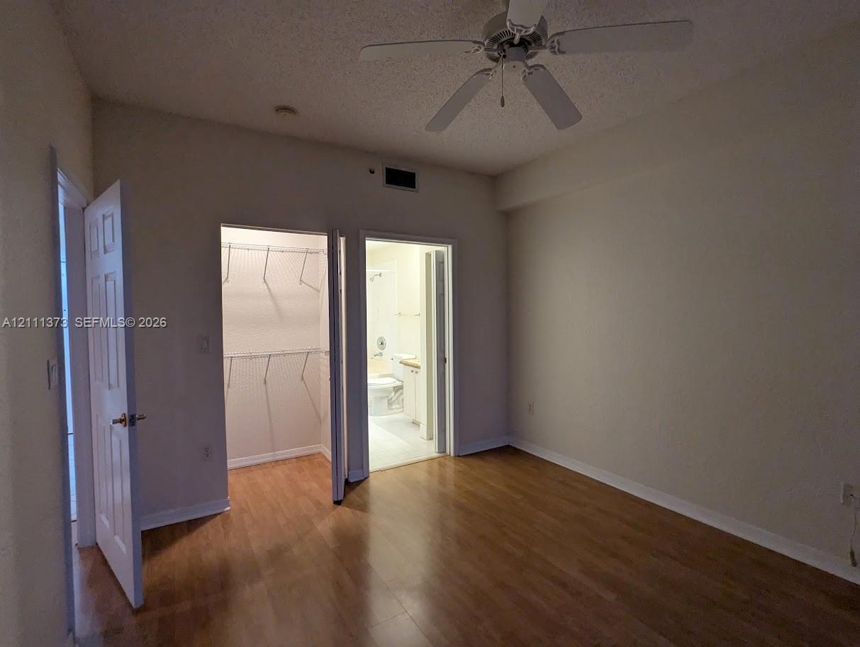 Wood-finish flooring, ceiling fan with integrated lighting, reach-in closet with wire shelving, and interior panel doors