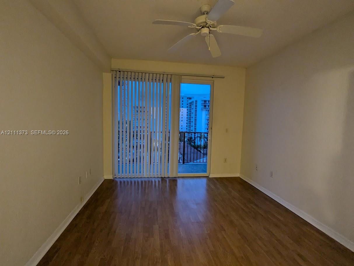Interior space featuring wood-finish flooring, a ceiling fan with integrated light fixture, and floor-to-ceiling glass sliding doors opening to a balcony Interior space featuring wood-finish flooring, a ceiling fan with integrated light fixture, and floor-to-ceiling glass sliding doors opening to a balcony