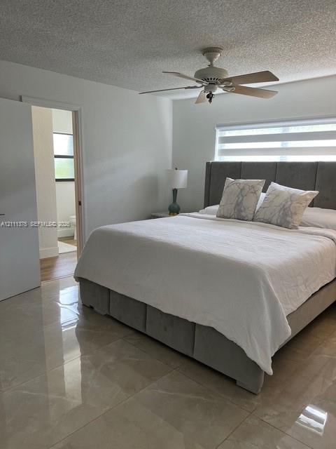 Large-format tile flooring, textured ceiling, ceiling fan with light fixture, and window with horizontal blind
