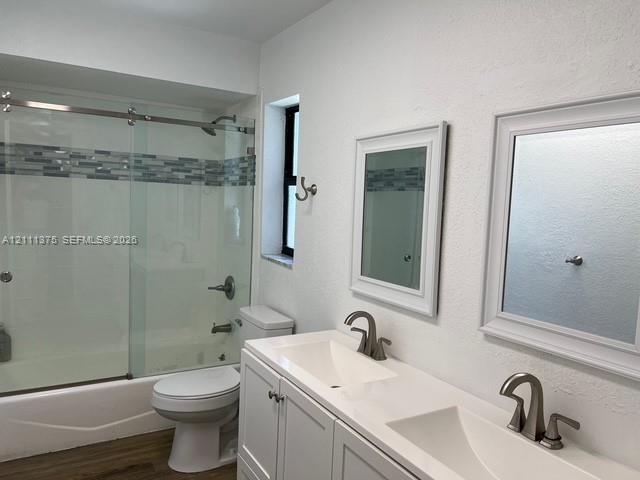 Double vanity featuring white cabinetry, a solid surface countertop with dual integrated sinks, and brushed nickel hardware