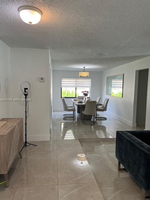 Large-format tile flooring, drum pendant lighting, flush-mount ceiling fixture, and dual-layered window shades