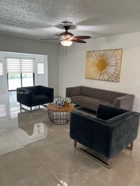 Large-format tile flooring, multi-pane sliding glass door with horizontal blinds, and a ceiling-mounted light fixture with fan blades