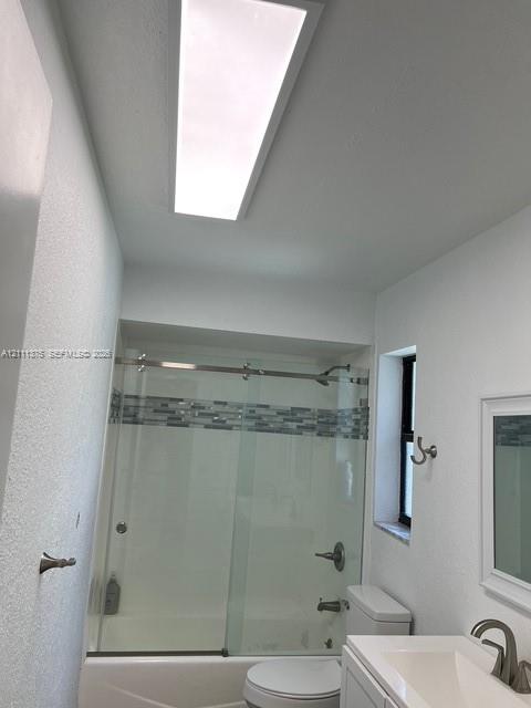 Bathroom featuring a glass-enclosed shower with decorative tile inlay, rectangular vanity with a brushed metal faucet, rectangular ceiling light fixture, and a single window