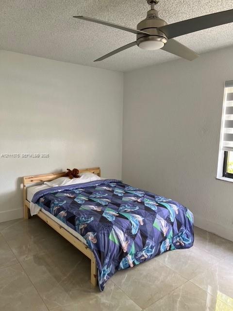 Neutral-toned large-format tile flooring, brushed-nickel ceiling fan with integrated lighting, and horizontal window shades