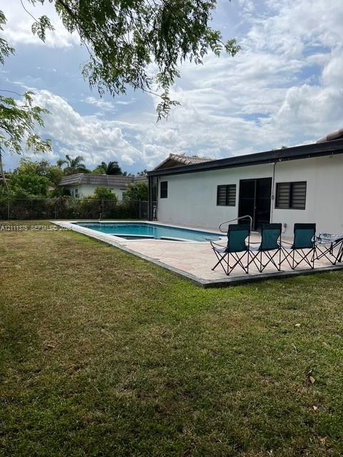 In-ground swimming pool featuring a concrete deck and a fenced backyard