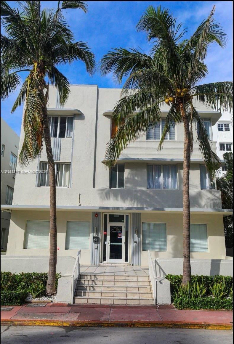 Art Deco exterior featuring a symmetrical facade, concrete-framed windows, vertical decorative fluting, and elevated stone entry stairs