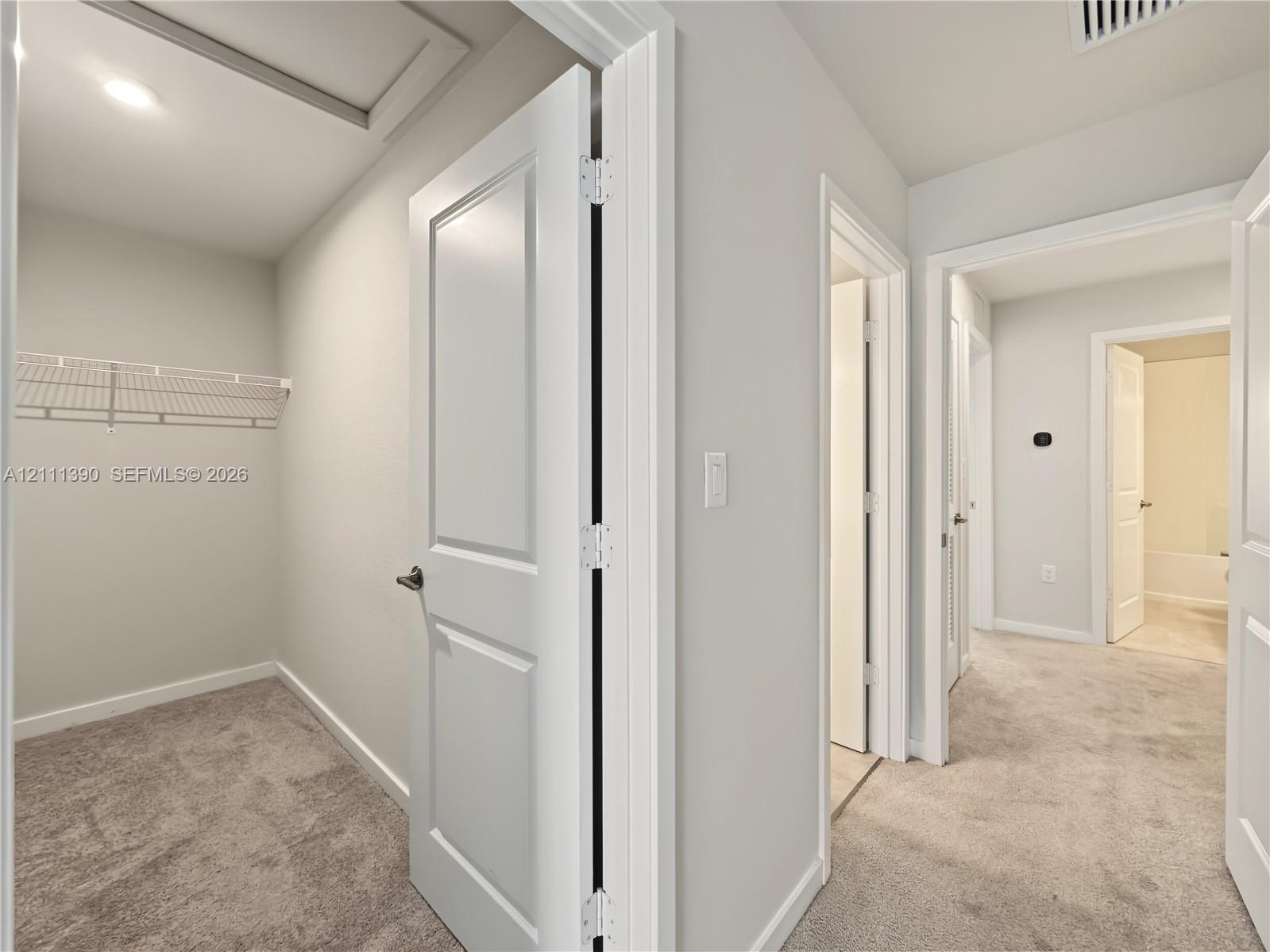 Interior space featuring neutral-toned carpeting, two-panel interior doors, and a built-in wire shelving system