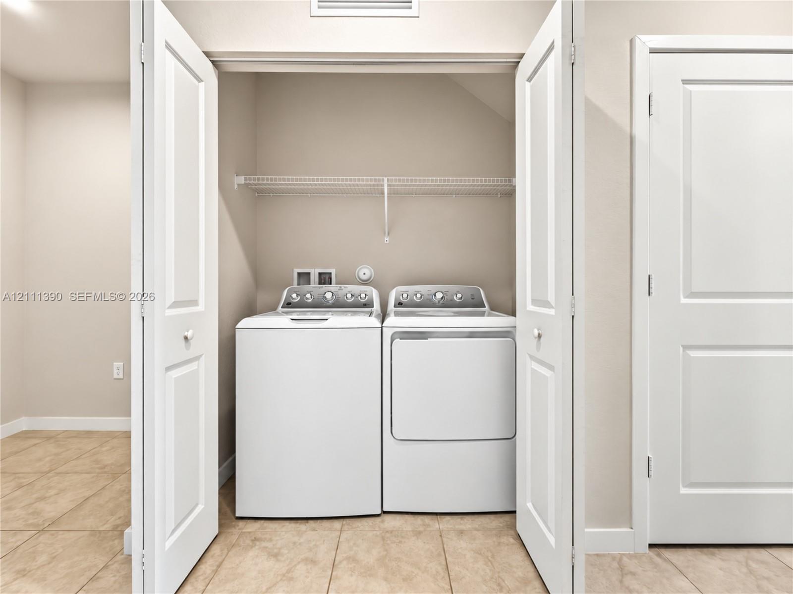 Laundry closet featuring double panel doors, wire shelving, and tile flooring