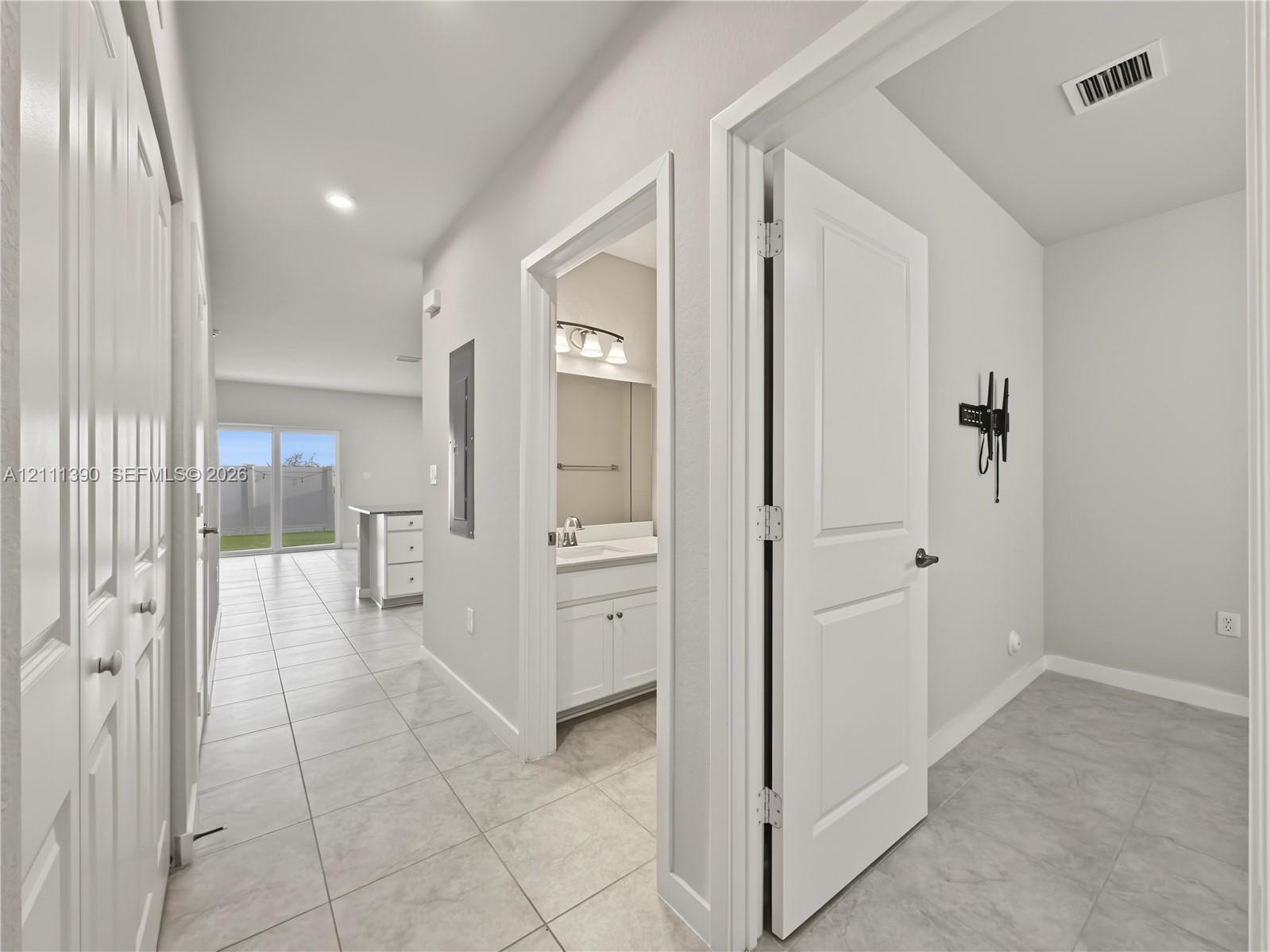 Interior hallway featuring large-format tile flooring, white panel doors, and neutral wall tones