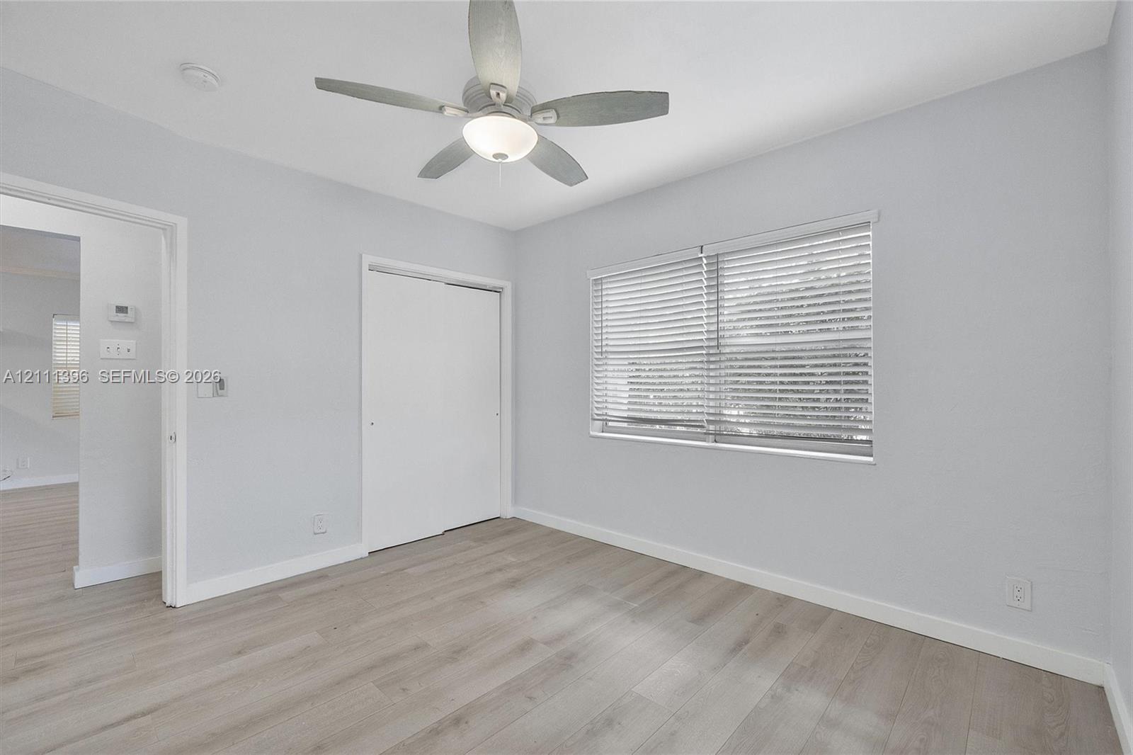 Room featuring wood-finish flooring, a ceiling fan with integrated lighting, and a closet with sliding doors