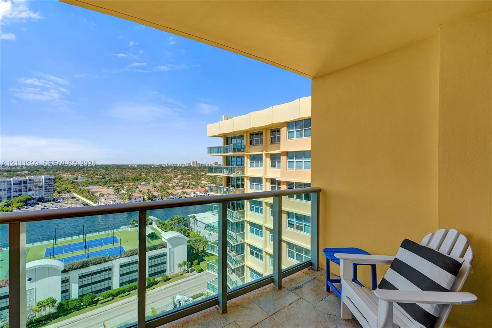 Covered balcony featuring stone-tile flooring and a metal railing with glass panels