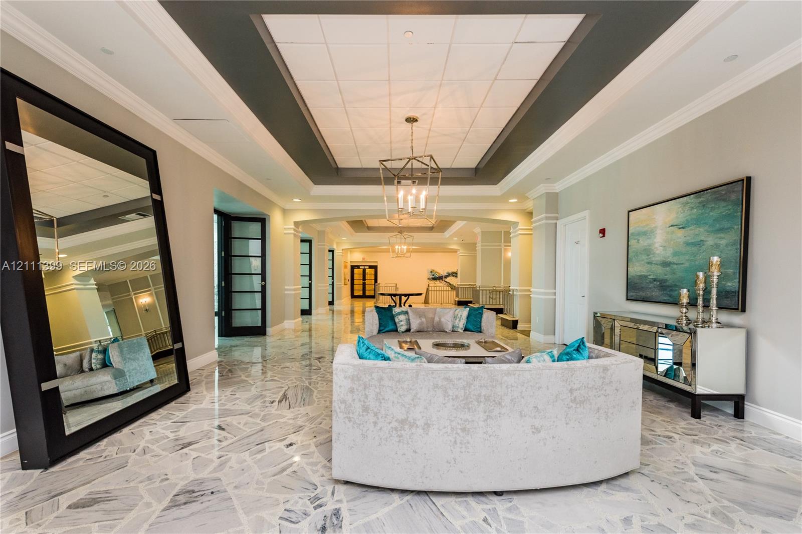 Expansive foyer featuring polished stone flooring with a mosaic pattern, coffered ceilings, crown molding, and metal lantern-style chandeliers