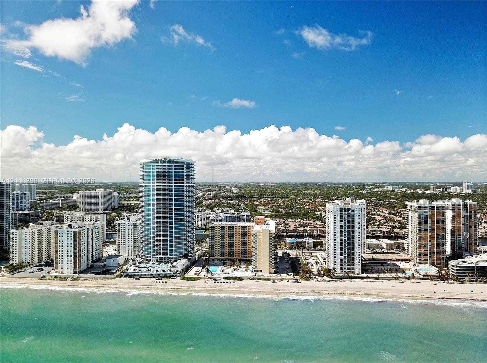 Aerial perspective of coastal high-rise development featuring direct beach access, expansive shoreline frontage, and proximity to the Atlantic Ocean