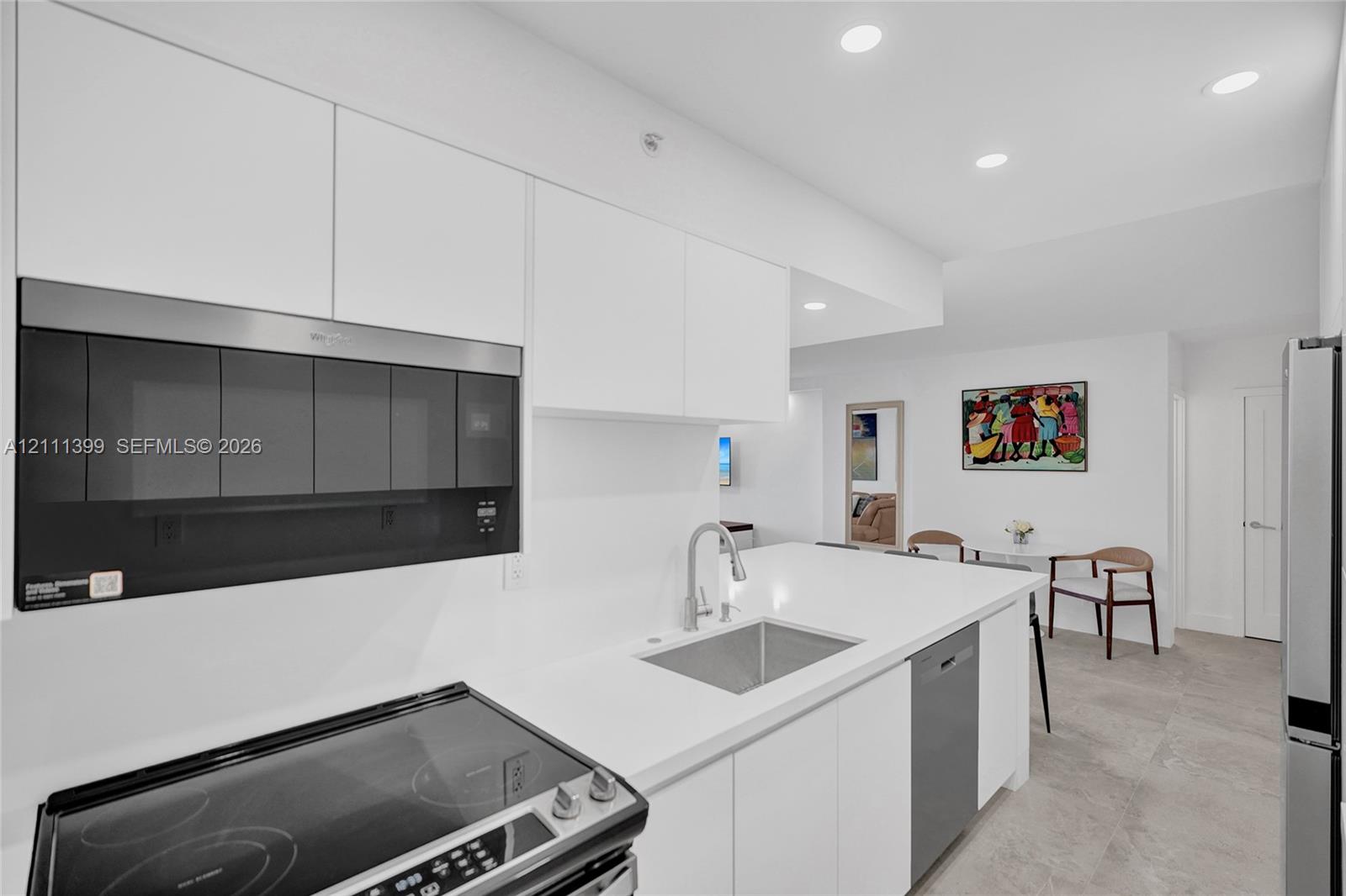 Kitchen featuring flat-panel white cabinetry, solid surface countertops, stainless steel appliances, an undermount sink with a gooseneck faucet, and recessed lighting