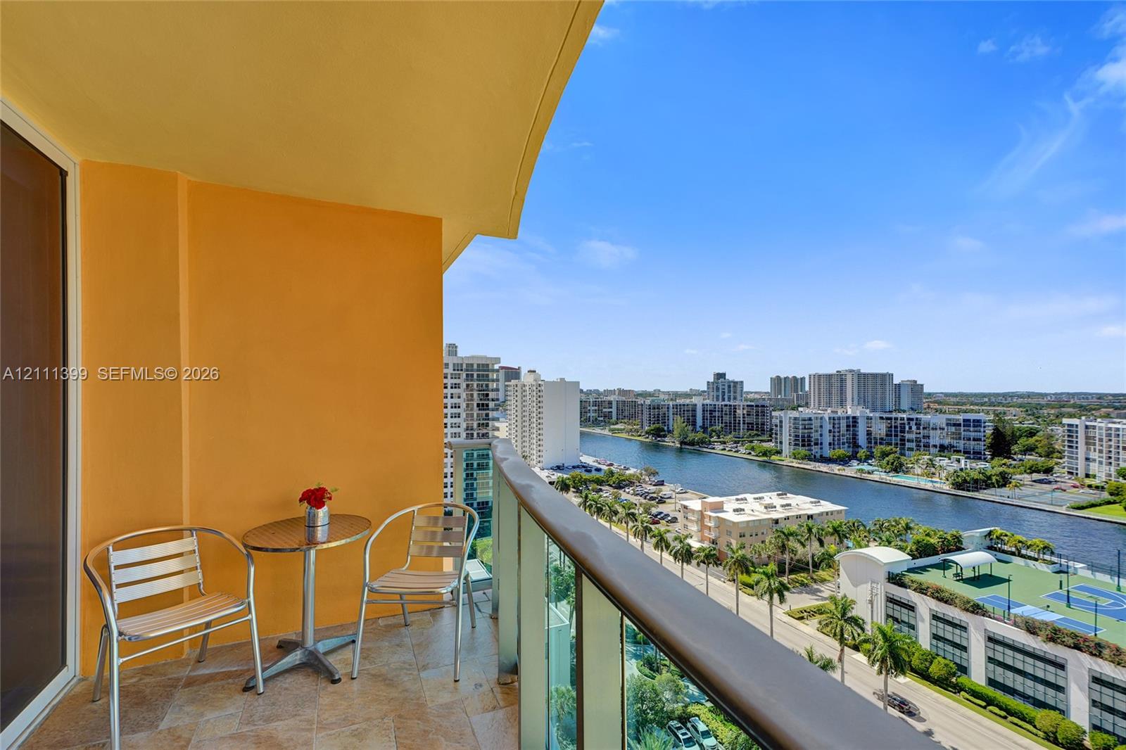 Private balcony featuring stone-tiled flooring and a glass-panel railing with a metallic handrail
