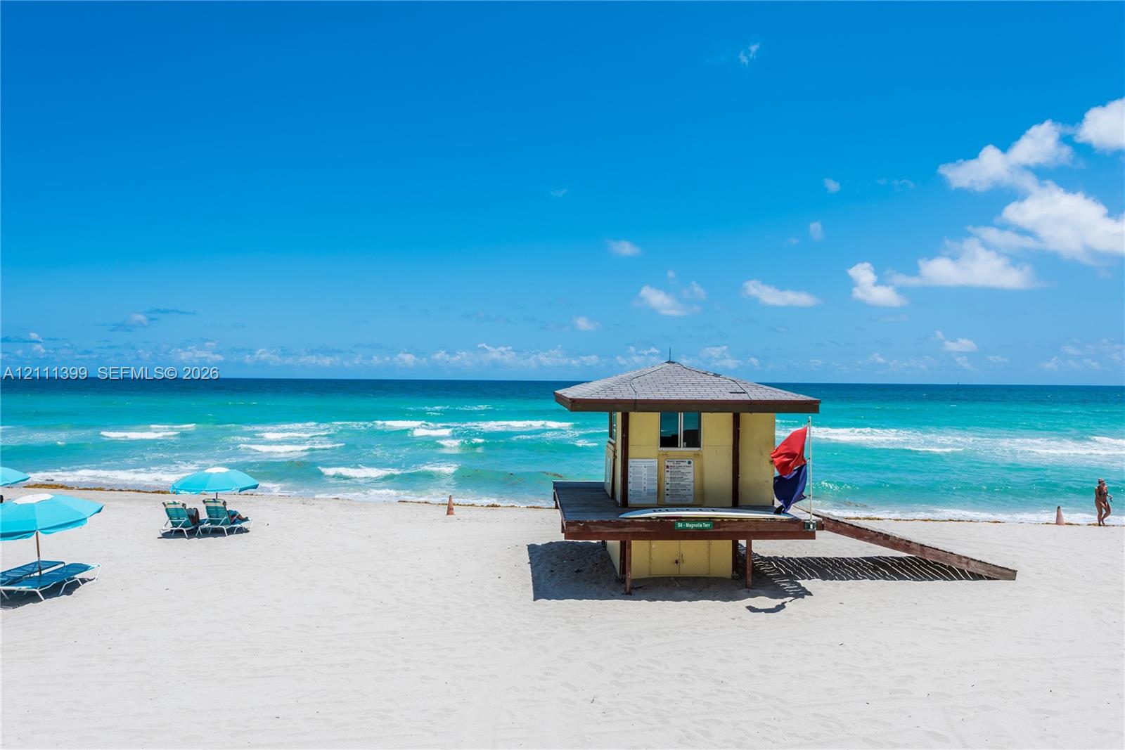 Sandy beachfront with direct ocean access and lifeguard station featuring a shingled roof and wood-plank ramp
