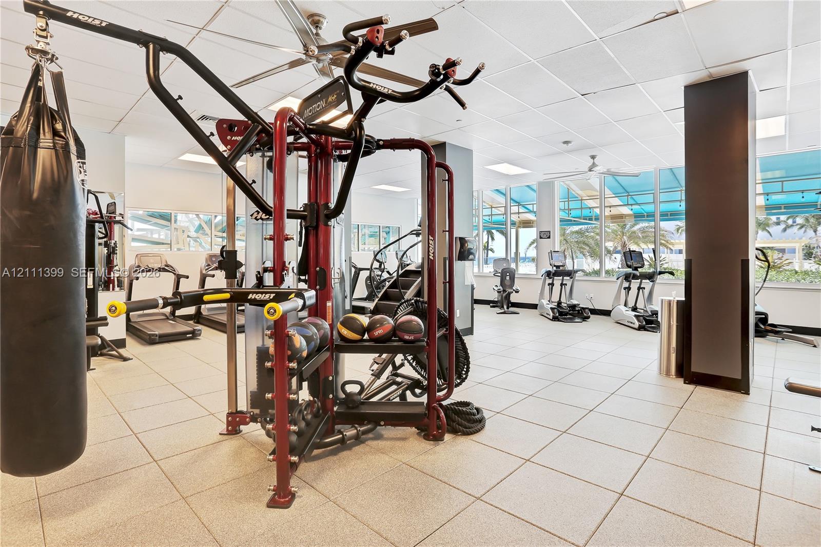 Fitness center featuring tile flooring, ceiling-mounted fans, recessed lighting, and floor-to-ceiling windows