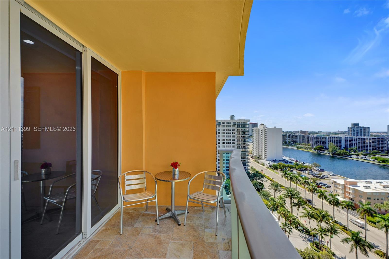 Covered balcony featuring stone flooring, floor-to-ceiling glass sliding doors, and a glass-paneled railing