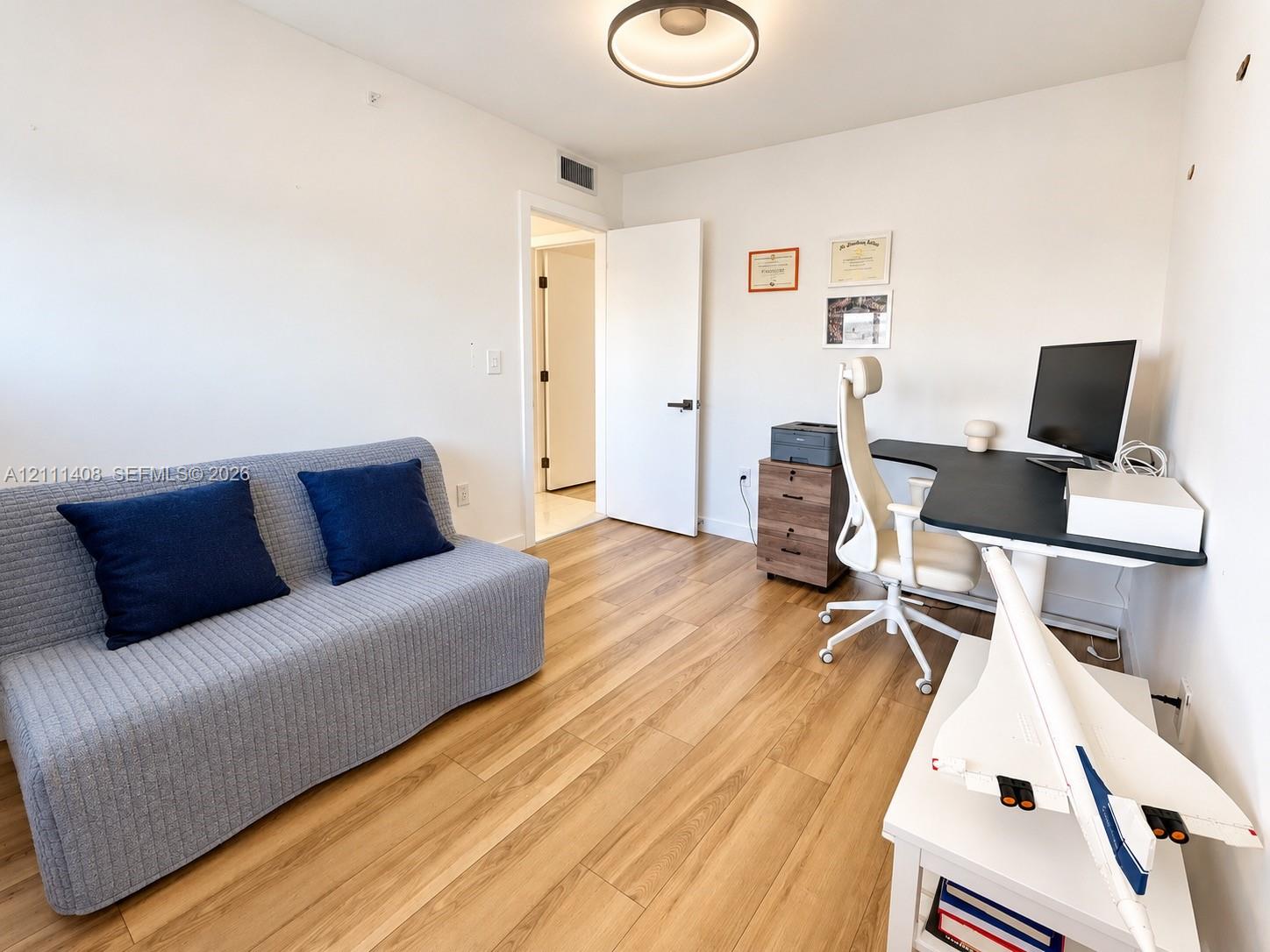 Room featuring wood-finish flooring, a horizontal sliding window with roller shade, and a bi-fold closet door