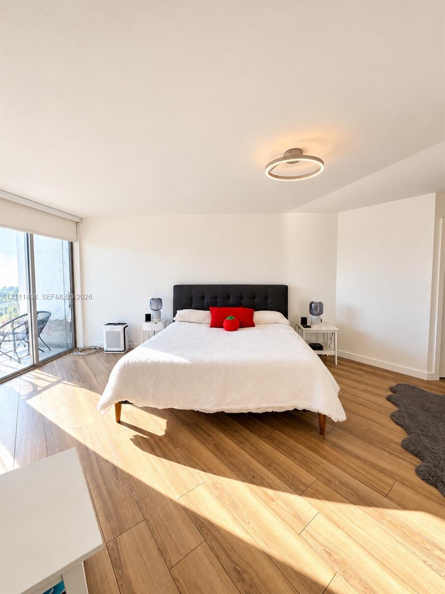 Wood-finish flooring, sliding glass door, and circular LED ceiling light fixture