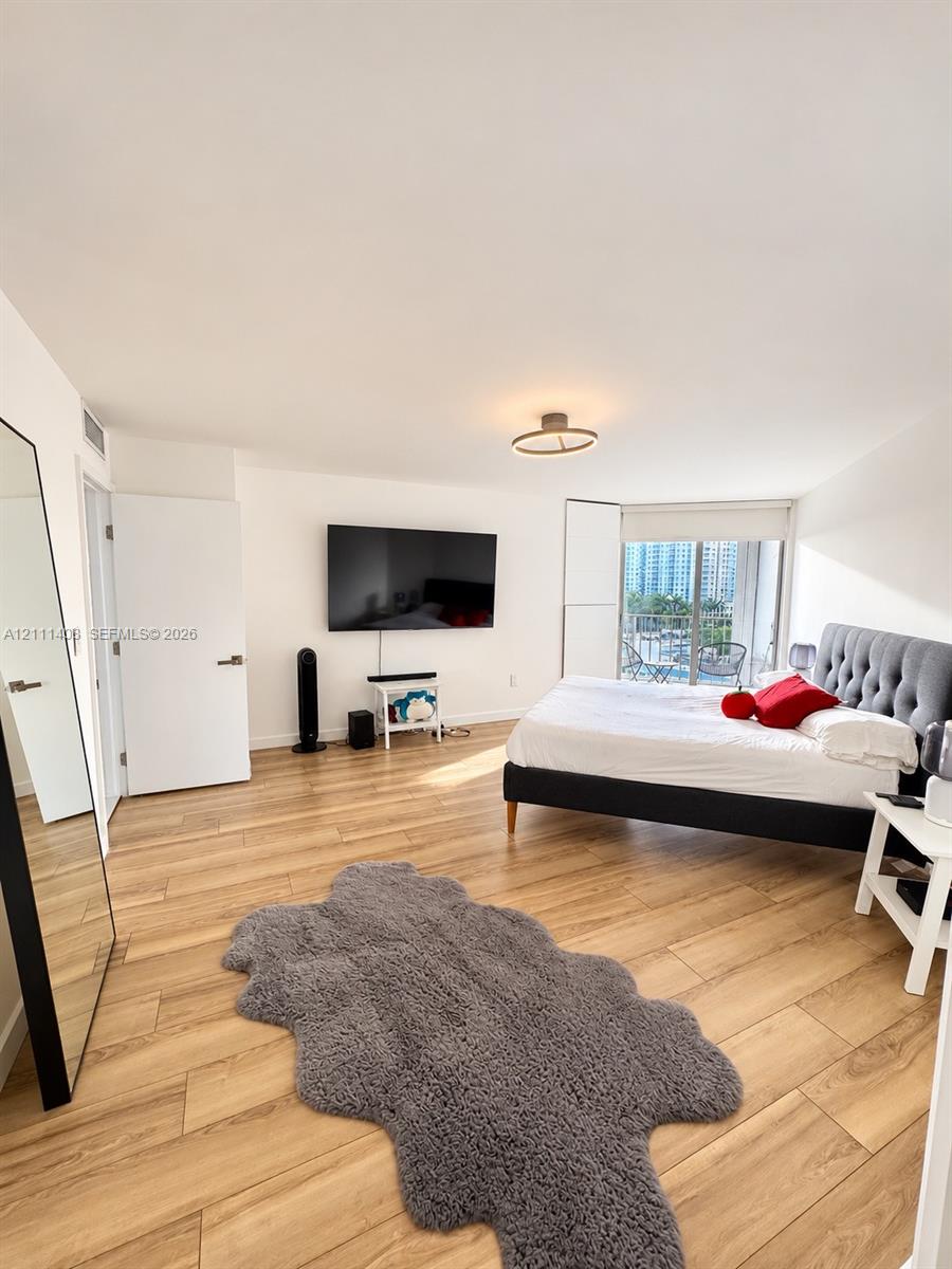 Wood-finish flooring, floor-to-ceiling sliding glass doors, and a modern circular LED ceiling fixture