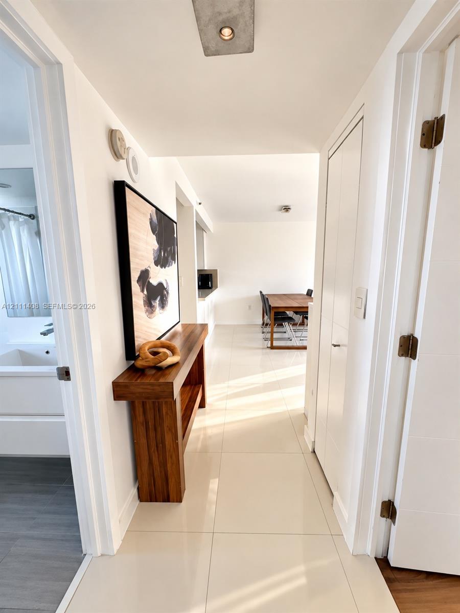 Open-concept interior featuring polished tile flooring, white cabinetry, stainless steel appliances, and flush-mount ceiling lighting