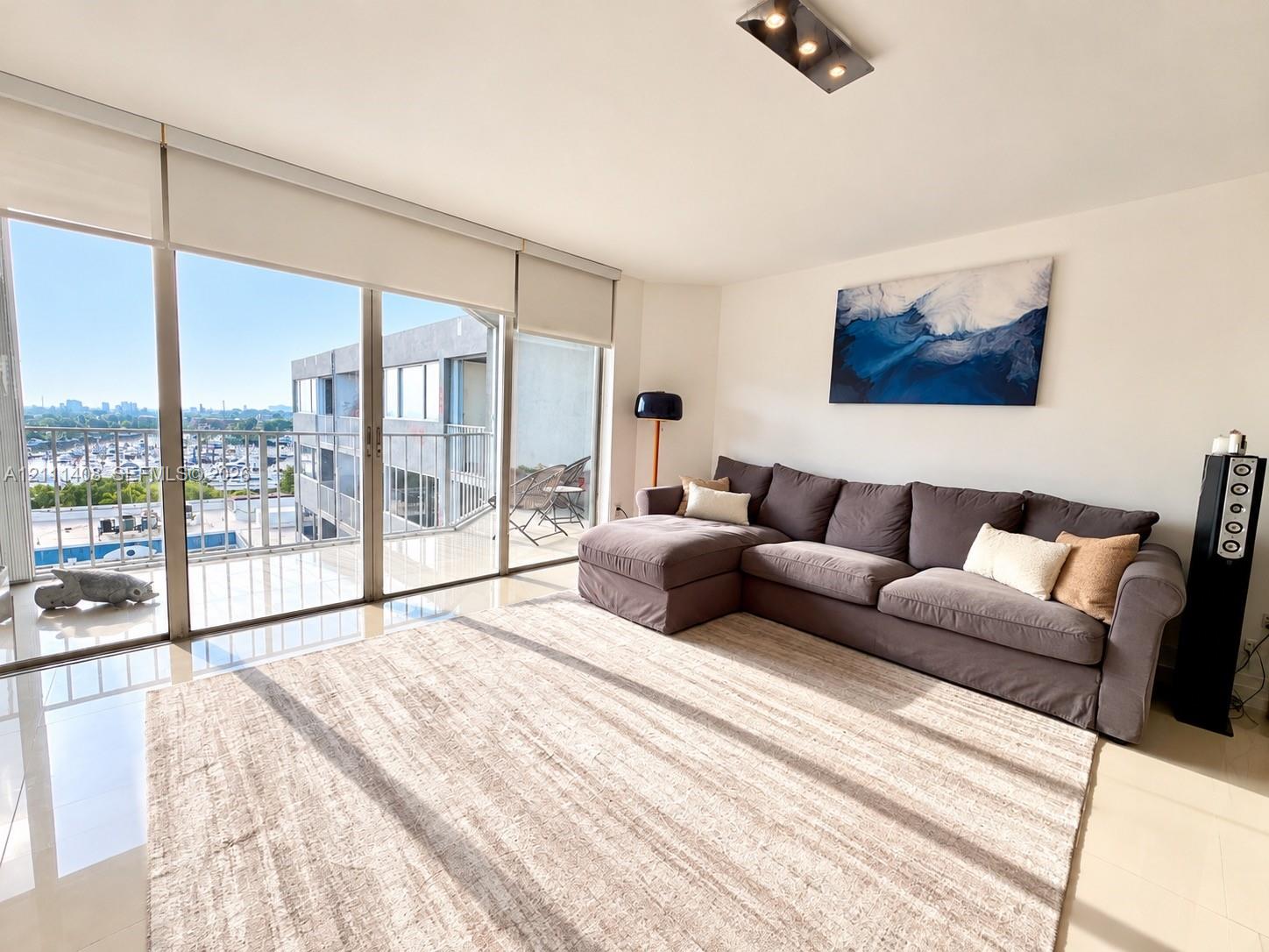 Open-concept living space featuring floor-to-ceiling glass sliding doors, polished tile flooring, and dual modern rectangular flush-mount ceiling light fixtures