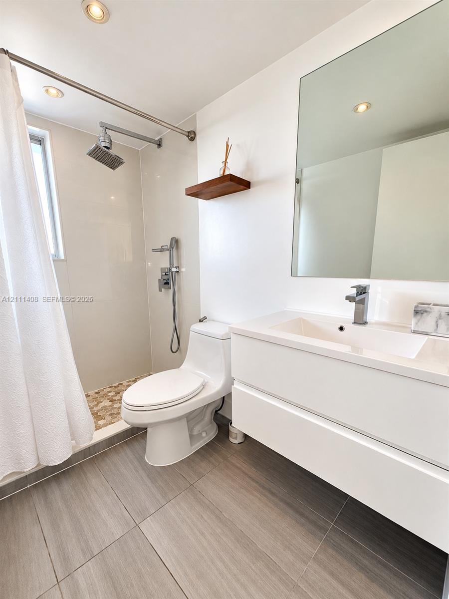 Room featuring wood-finish flooring, a circular modern flush-mount light fixture, and a built-in closet with double-panel doors