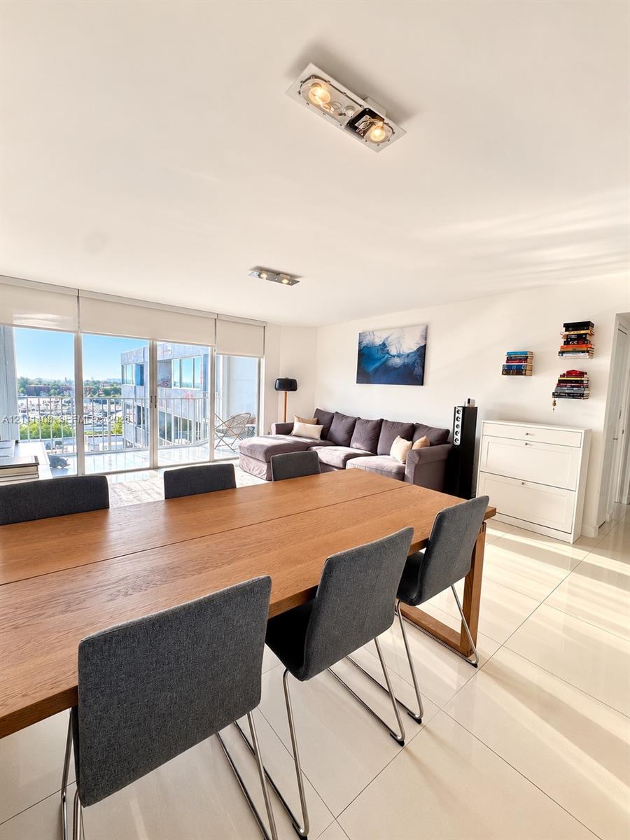 Large-format tile flooring, recessed ceiling lighting, and floor-to-ceiling glass sliding doors opening to a balcony with waterfront and city scenery