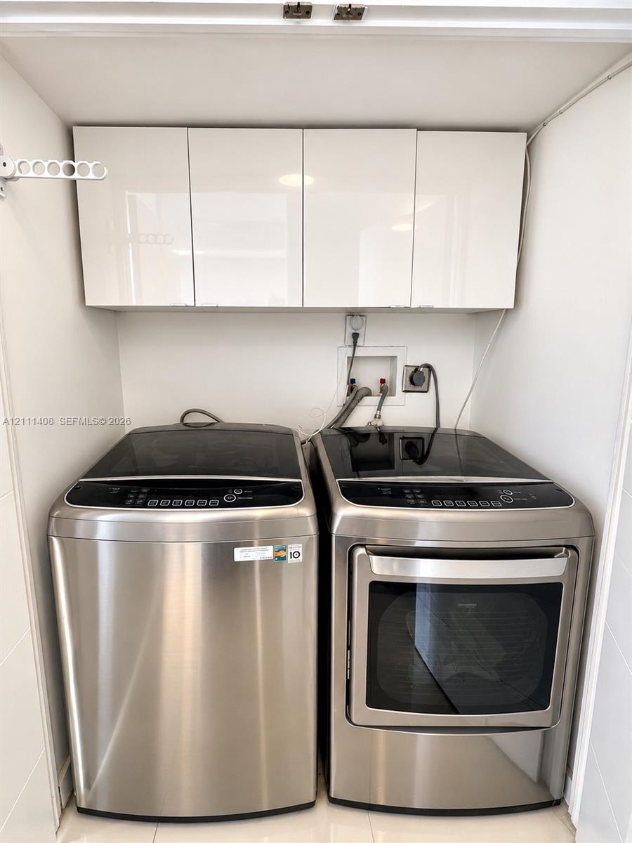 Kitchen featuring flat-panel white cabinetry, solid-surface countertops with a breakfast bar, stainless steel appliances, and a single-basin undermount sink with a gooseneck faucet