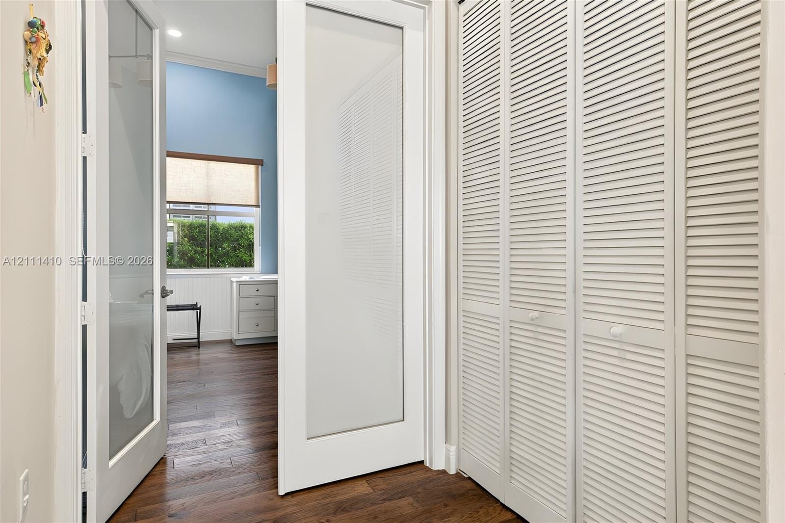 Interior space featuring wood-finish flooring, white louvered bifold closet doors, and a glass-panel door