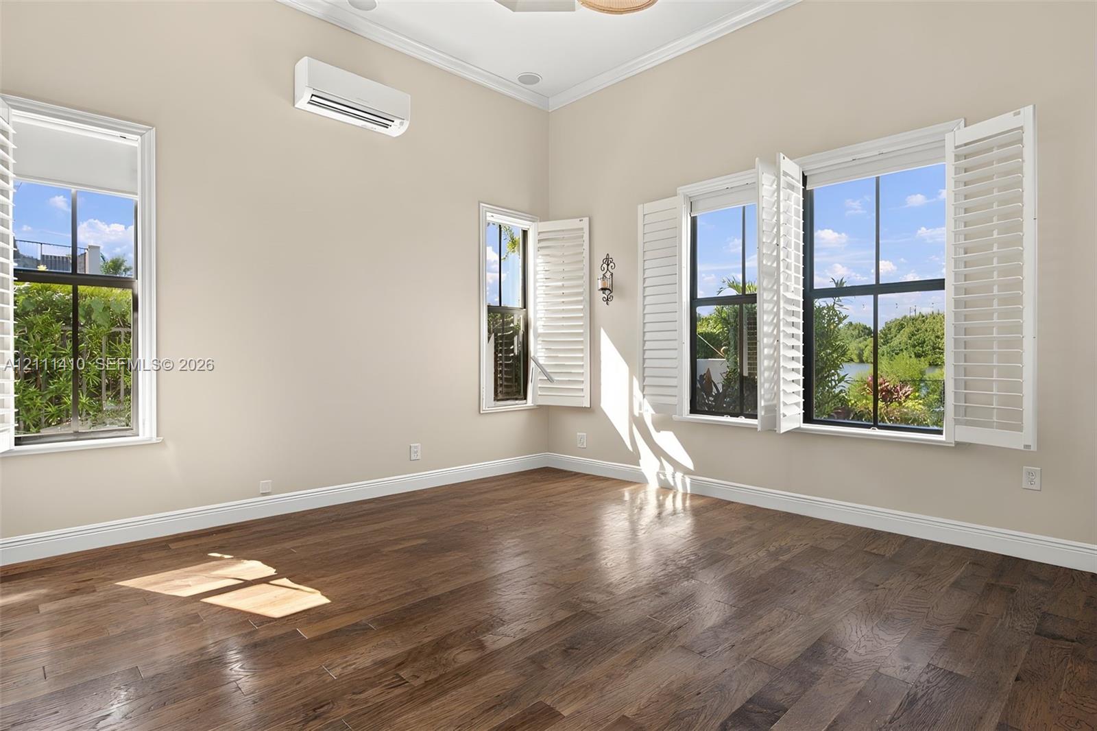 Interior space featuring wood-finish flooring, vaulted ceilings, dual-pane windows with plantation shutters, and a wall-mounted ductless air conditioning unit