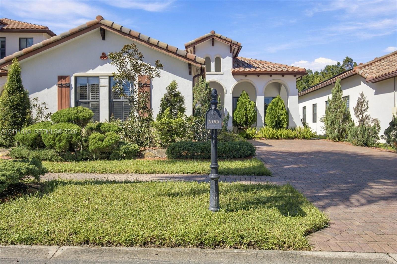 Stucco exterior with a clay tile roof, arched entryway, and paver driveway Stucco exterior with a clay tile roof, arched entryway, and paver driveway