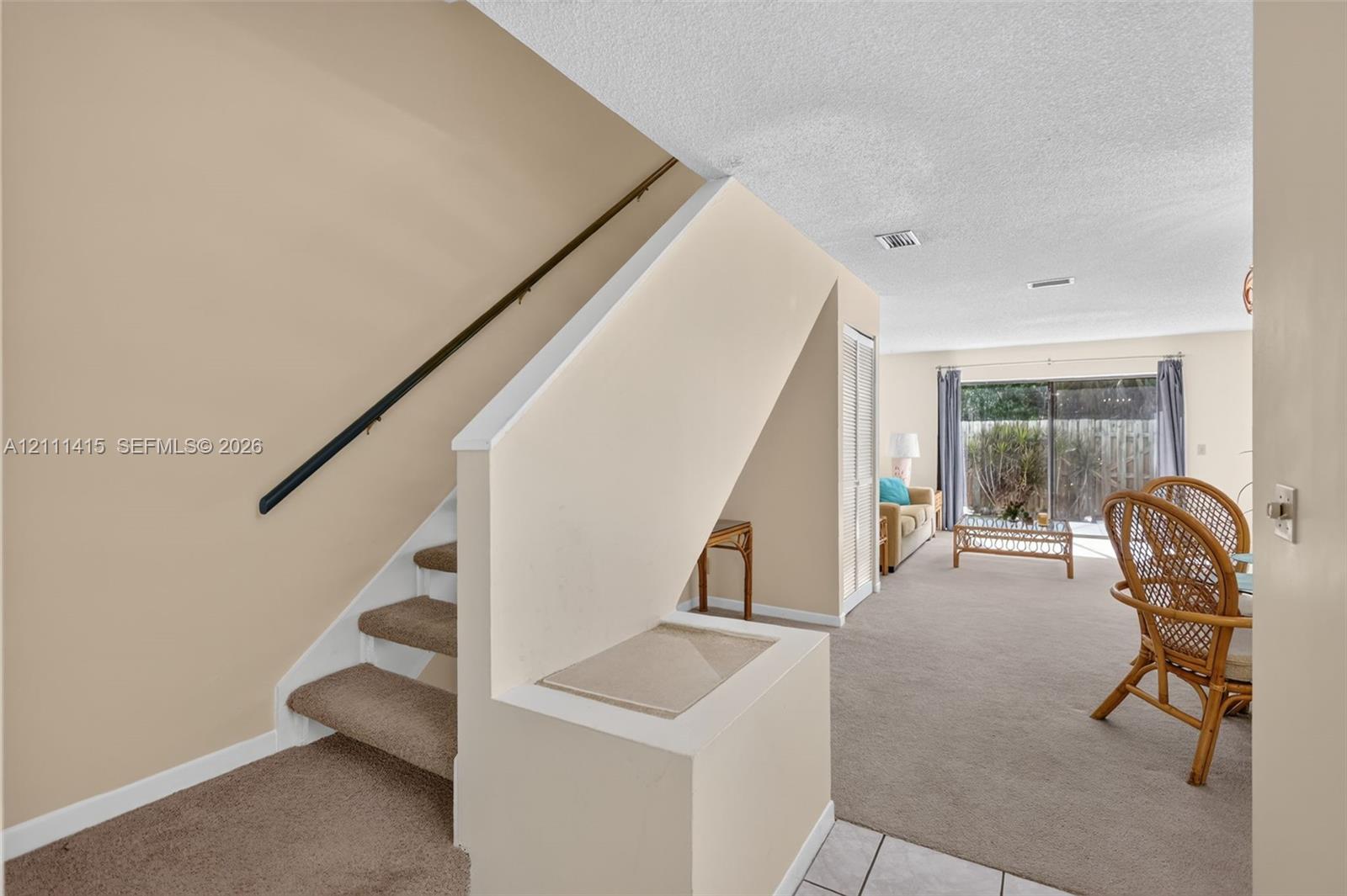Staircase featuring carpeted steps and a metal handrail, finished with neutral wall paint and a sliding glass door