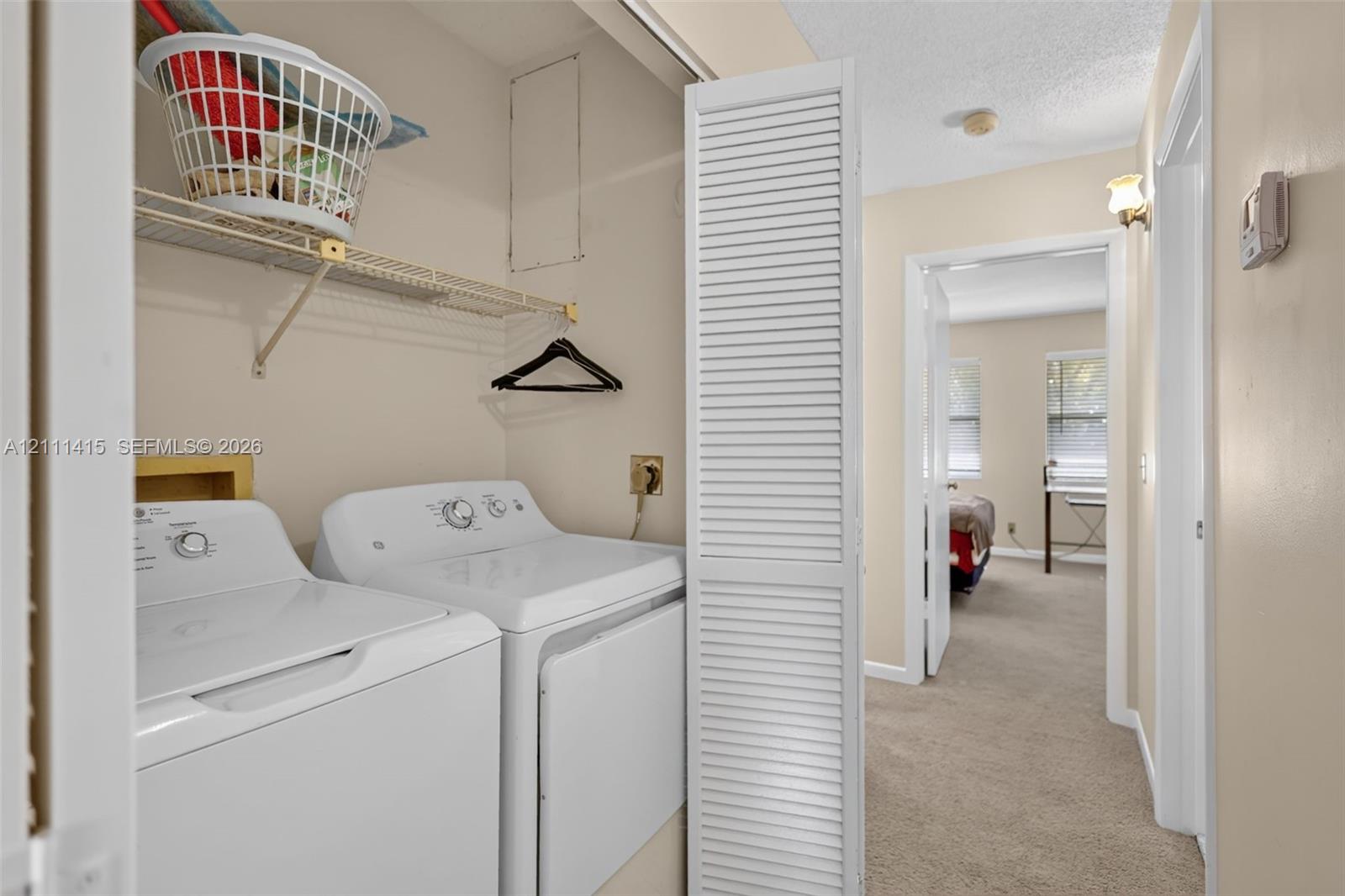 Laundry closet featuring bi-fold louvered doors and overhead wire shelving