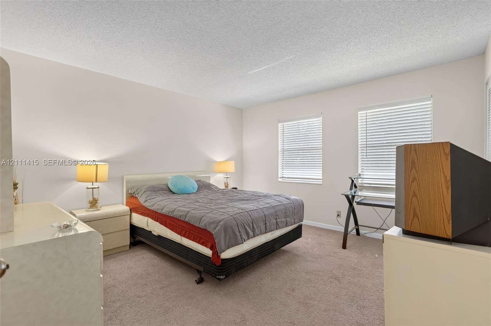 Neutral-toned walls, wall-to-wall carpeting, and dual windows equipped with horizontal blinds
