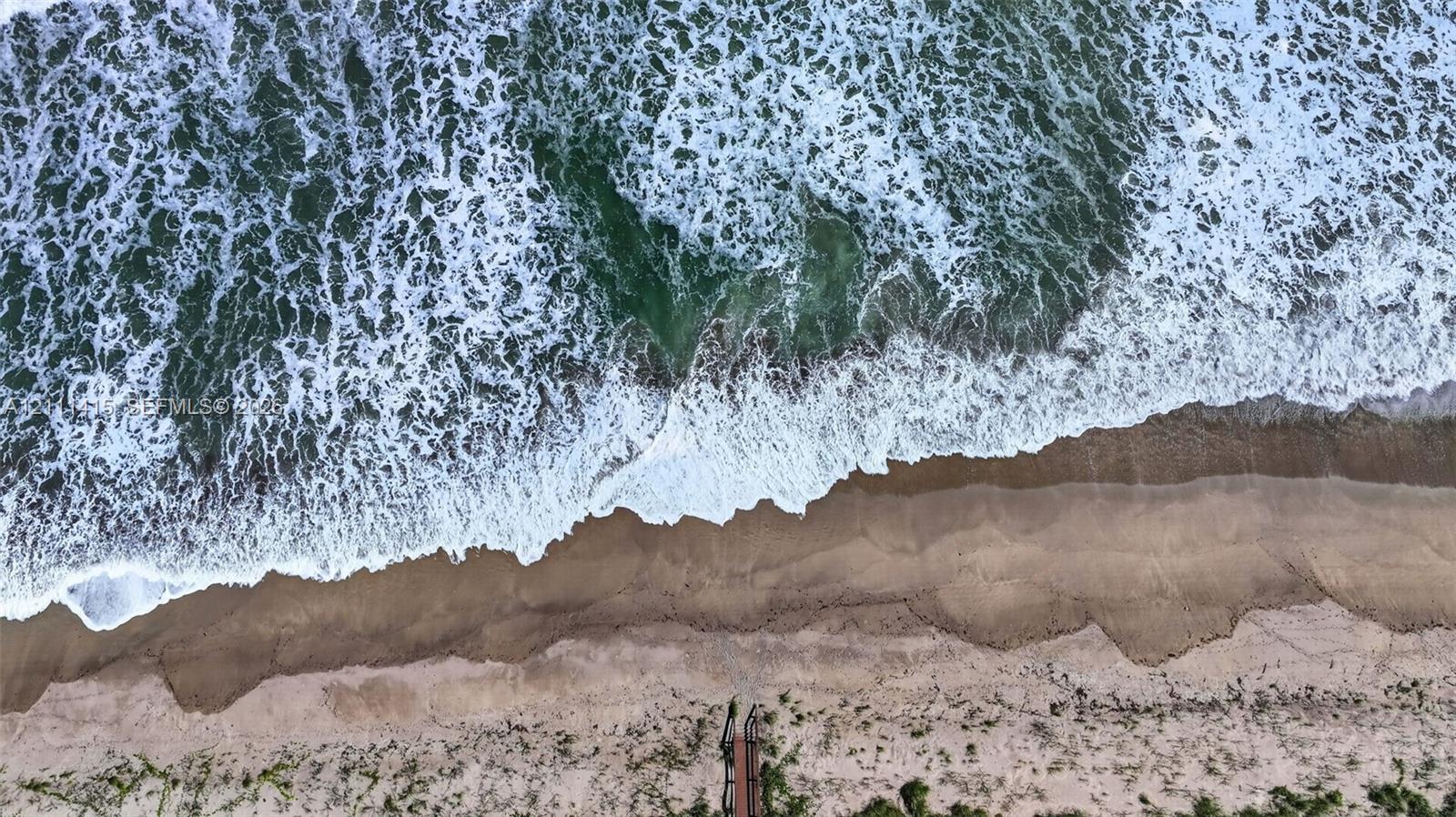 Direct oceanfront property featuring sandy beach access and a private stairway
