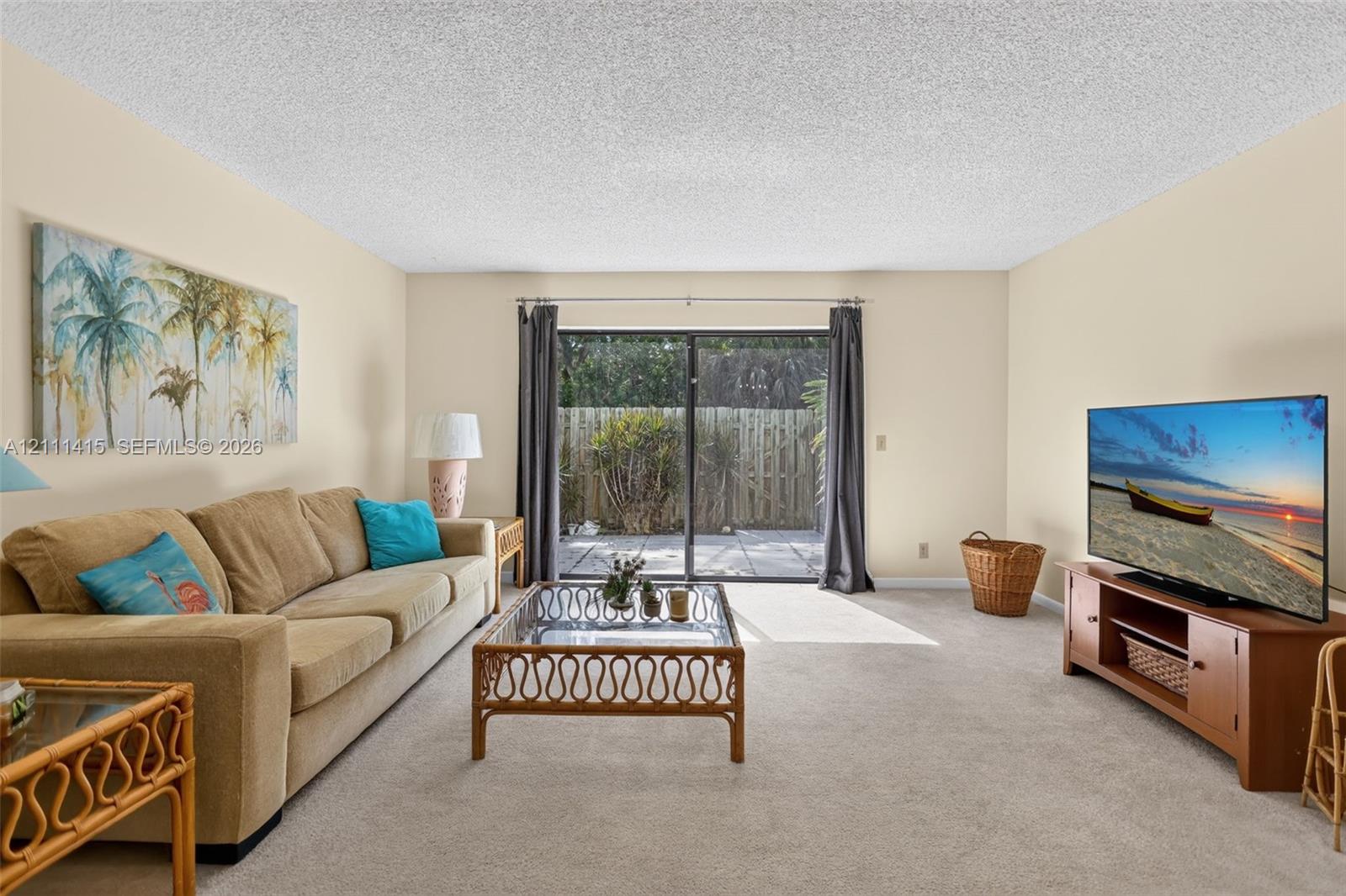 Living space featuring wall-to-wall carpeting, textured ceiling, and sliding glass door with external patio access