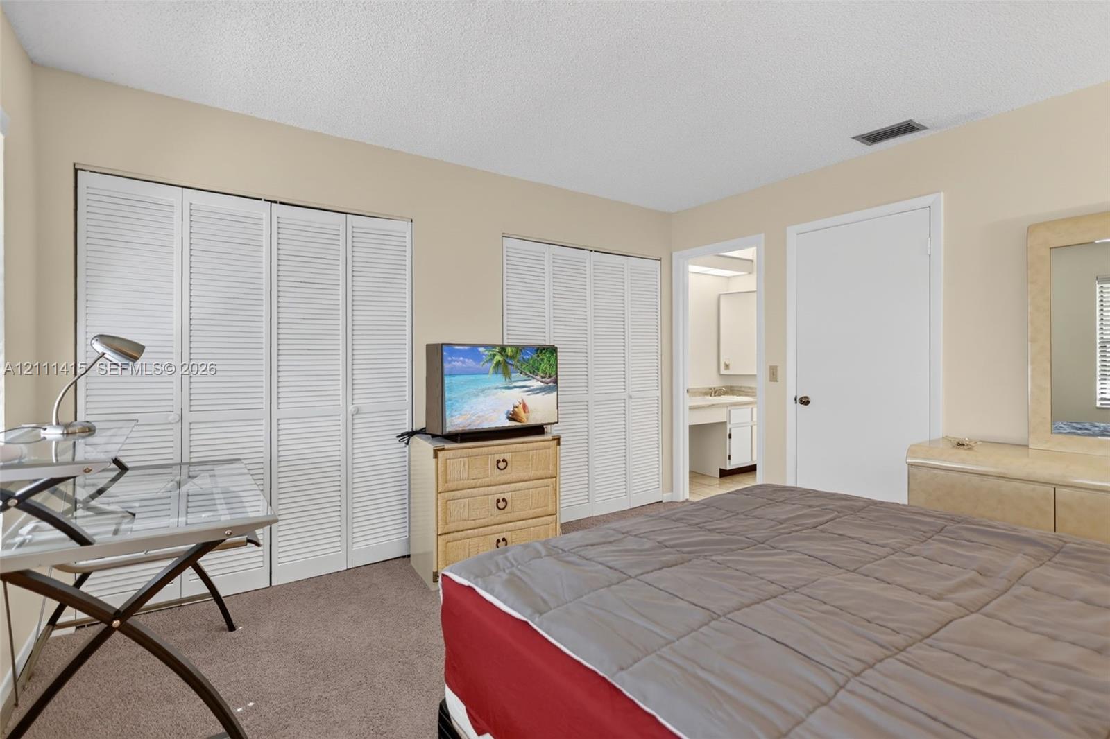 Neutral-toned interior featuring dual sets of white louvered-door closets and wall-to-wall carpeting