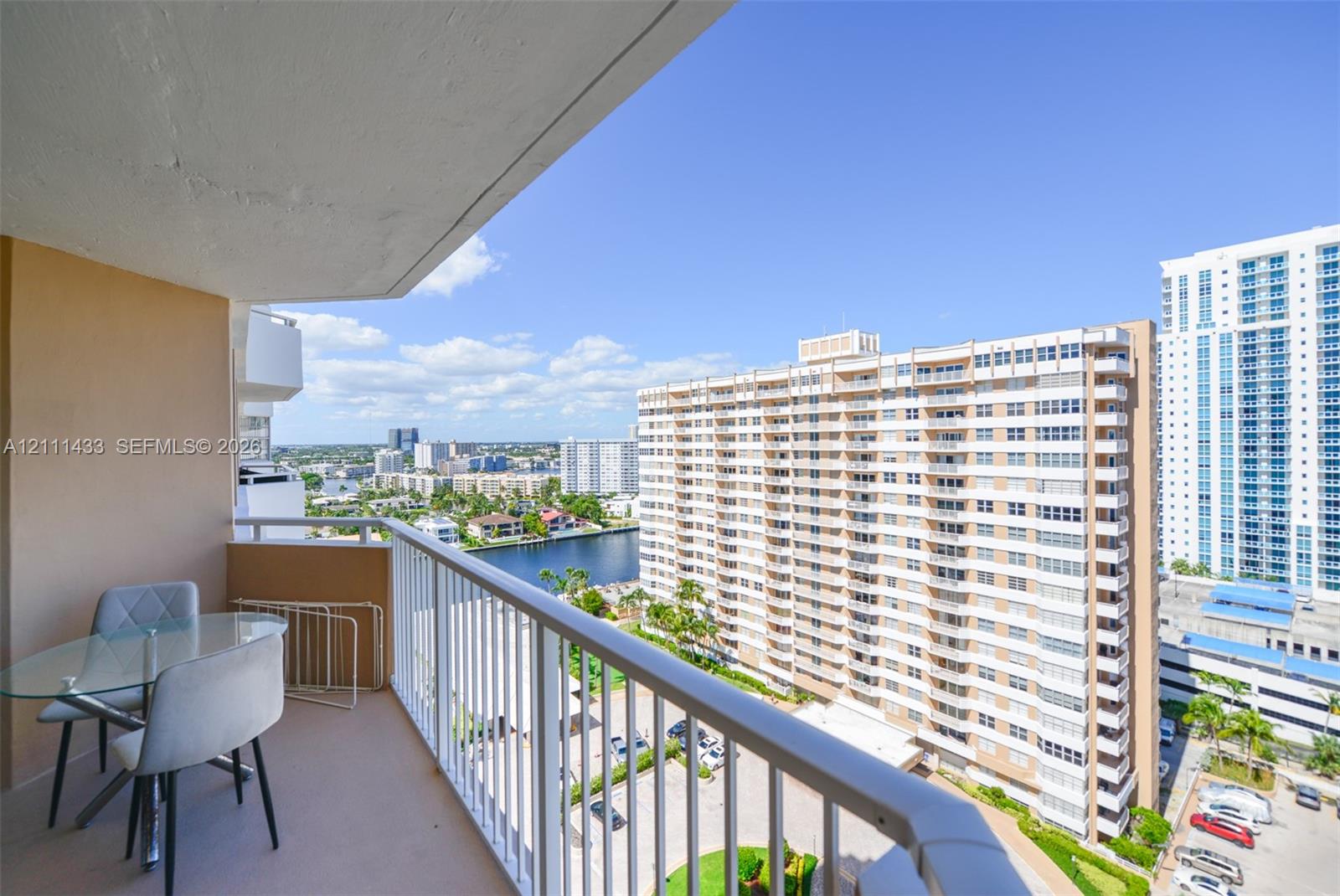 Covered balcony with a white metal railing and concrete flooring
