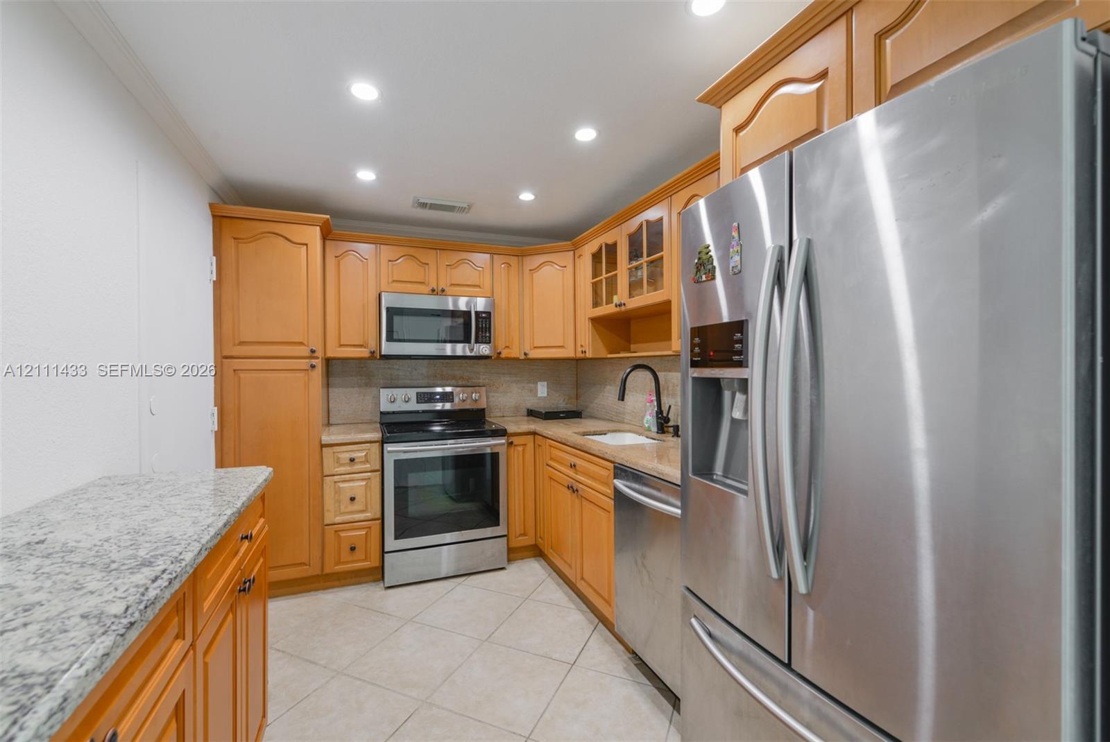 Kitchen featuring light wood cabinetry, stone countertops, stainless steel appliances, a tile floor, and recessed lighting
