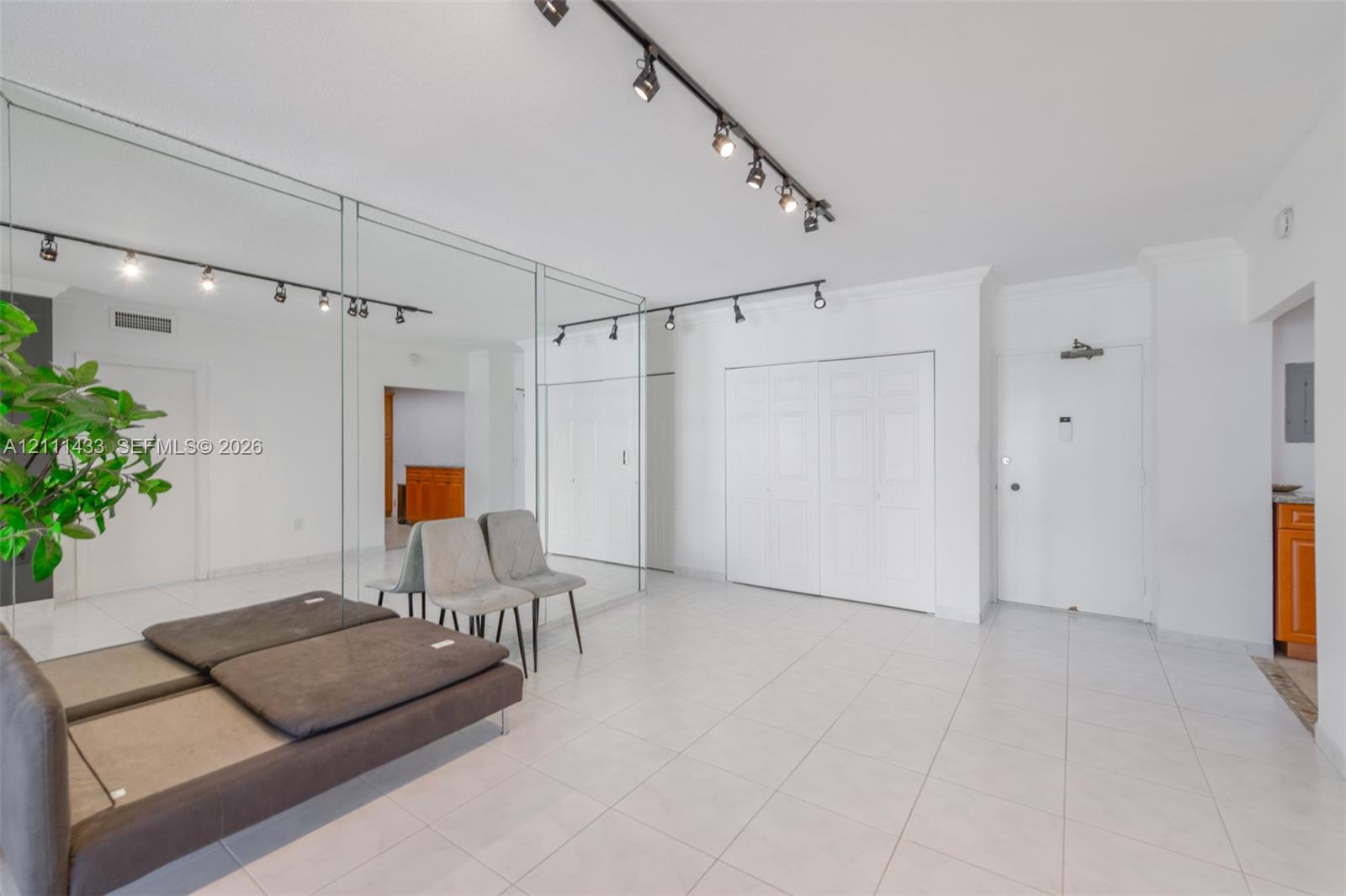 Floor-to-ceiling wall mirrors, track lighting, neutral tile flooring, and bi-fold closet doors